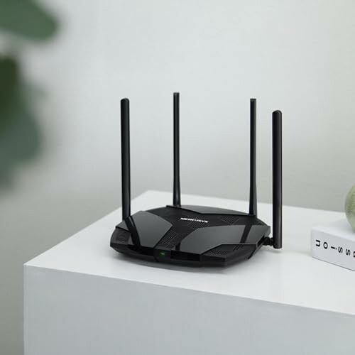 Black wireless router with four antennas on a white table.